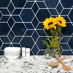 sunflowers in a vase on a kitchen counter with plates and utensils