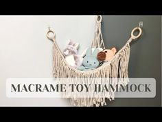 macrame toy hammock hanging on the wall with stuffed animals in it