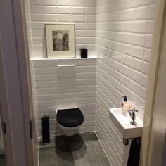 a white toilet sitting next to a sink in a bathroom under a framed picture on the wall