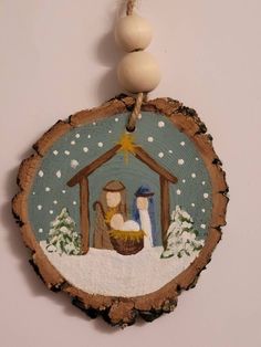 a christmas ornament with a nativity scene hanging from a string on a wall