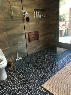 a bathroom with a toilet, shower and rugs on the floor in front of it