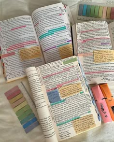 an open book with sticky notes on it next to some pens and colored paper clips