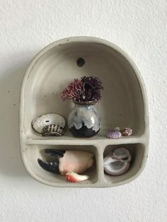 there is a vase with flowers and seashells in it on the wall shelf