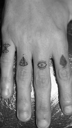 two fingers with tattoos on them and one has an eye in the middle, while the other