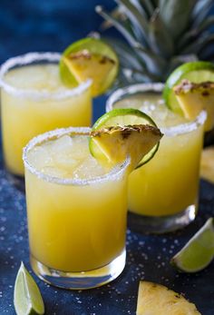 three glasses filled with pineapple margaritas and garnished with lime