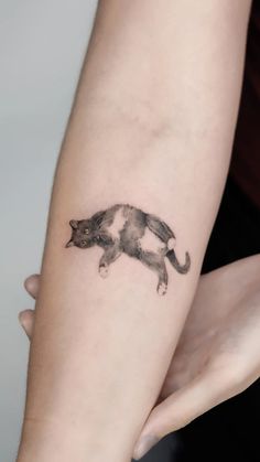 a cat tattoo on the arm of a woman's left arm, which is black and white