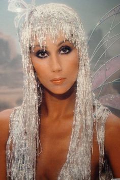 a woman with long white hair and tinsel on her face is posing for the camera