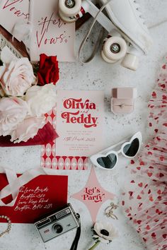 the wedding stationery is laid out on the table with flowers, sunglasses and other items