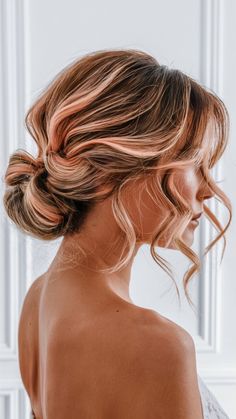 This low bun features soft peach pastel highlights interwoven with natural dark roots for a subtle yet elegant contrast. Loose curls frame the face, while rose gold pastel tones add a modern finish. This timeless style suits any special occasion. Romantic Low Bun, Peach Highlights, Low Bun, Dark Roots, Loose Curls