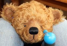 a brown teddy bear with a pacifier in its mouth sitting on someone's lap