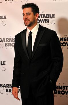 a man in a suit and tie standing on a red carpet with his hands in his pockets