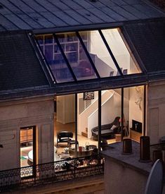 an apartment building is lit up at night with its windows open and the roof illuminated