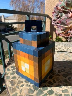 a planter made out of lego blocks sitting on a patio table next to a potted plant