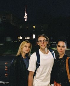 three young people standing next to each other in front of a building with a spire