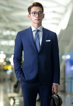 a young man in a suit and tie holding a briefcase while standing in an airport