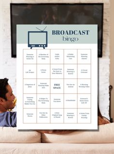 a man sitting on top of a couch in front of a poster with the words broadcast bingo