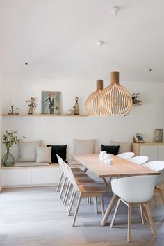 a dining room table with white chairs and hanging lights