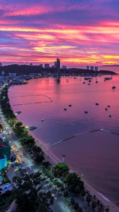 an aerial view of a city at sunset with boats in the water and buildings on both sides