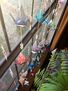 some origami birds hanging from a window