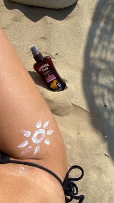 a woman's legs with white paint on them and a bottle of sunscreen