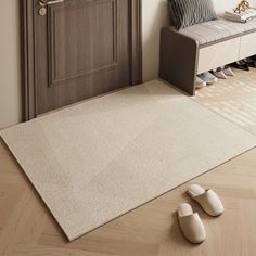 a beige rug with slippers on the floor in front of a wooden door and bench