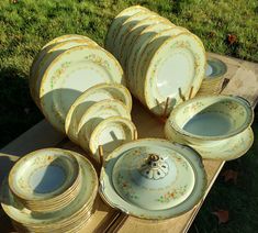 a table topped with lots of plates and bowls on top of a wooden table covered in grass