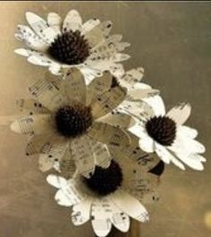 three paper flowers in a vase with music notes on the stems and sheet music behind them