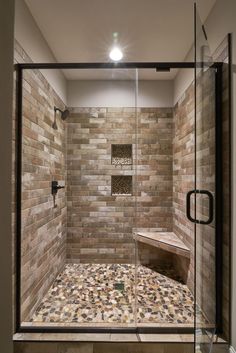 a walk in shower sitting next to a tiled wall and floor with a bench on the side