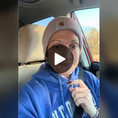 a woman wearing a blue hoodie is sitting in the back seat of a car