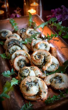 small pastries are on a wooden tray with greenery