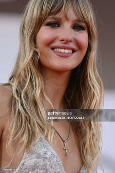 a smiling woman with long blonde hair wearing a silver dress