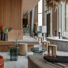 a living room filled with lots of furniture and decor on top of wooden floors next to tall windows