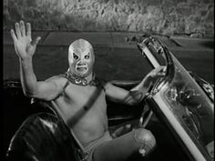 a man wearing a mask sitting in a car with his hand up to the side