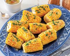 grilled corn on the cob with parsley and butter in a blue plate