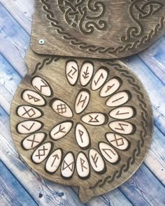 two wooden plaques with designs on them sitting on a wood floor next to each other