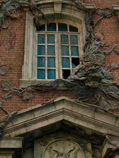 an old brick building with a clock on the side and vines growing out of it