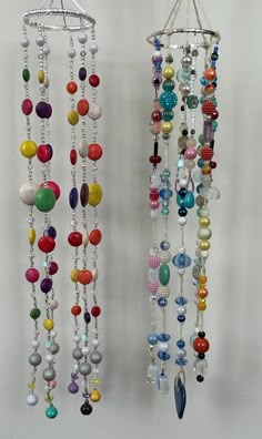 two wind chimes hanging on the side of a wall with beads attached to them