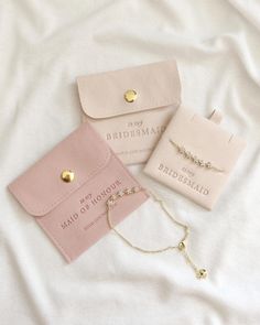 three bridesmaid jewelry laying on top of a white bed next to each other