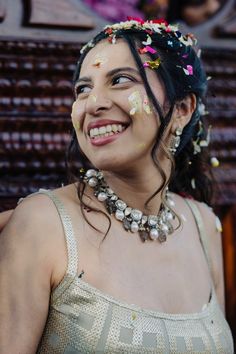 a woman with flowers all over her face and hair smiling at the camera while wearing a necklace