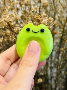 a hand holding a green donut with a smiley face on it's side