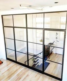 an empty room with glass walls and wooden floors