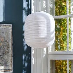 a white lamp hanging from the ceiling next to a window with green walls and windows behind it