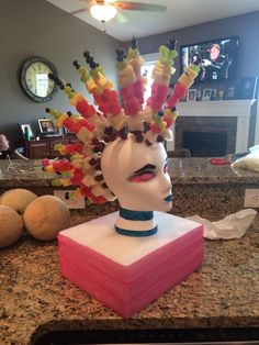 a woman's head is made out of candy sticks and fruit on the counter