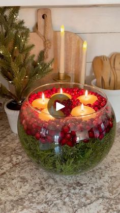 a bowl filled with candles sitting on top of a counter next to a christmas tree