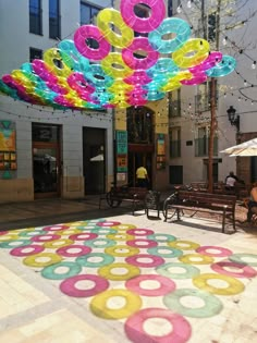 an outdoor area with various colored circles on the ground and people sitting at tables under umbrellas