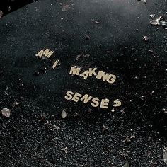 the word am i making sense written in yellow ink on a black piece of pavement