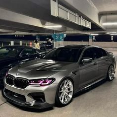 two cars parked in a parking garage next to each other with people looking at them