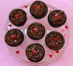 chocolate cupcakes with sprinkles and hearts on a plate