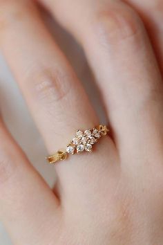 a woman's hand with a gold ring on it and three small flowers in the middle