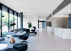 a living room filled with lots of furniture and large glass windows next to a kitchen